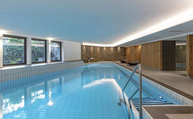 Indoor lap pool with integrated waterfall and poolside lounge seating