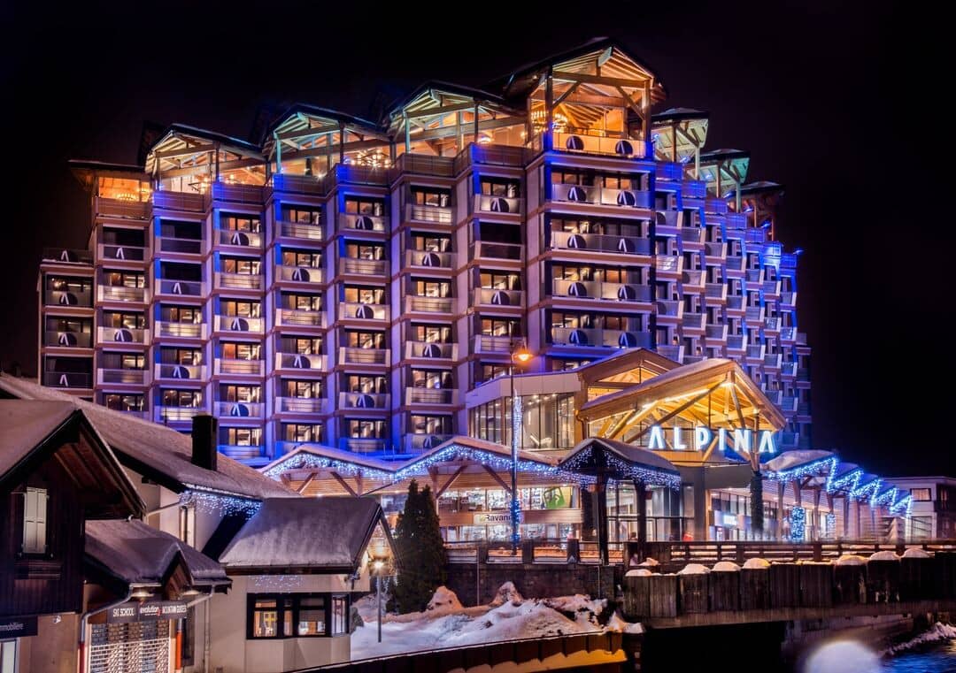 Hotel Alpina exterior at night with private balconies and mountain architecture