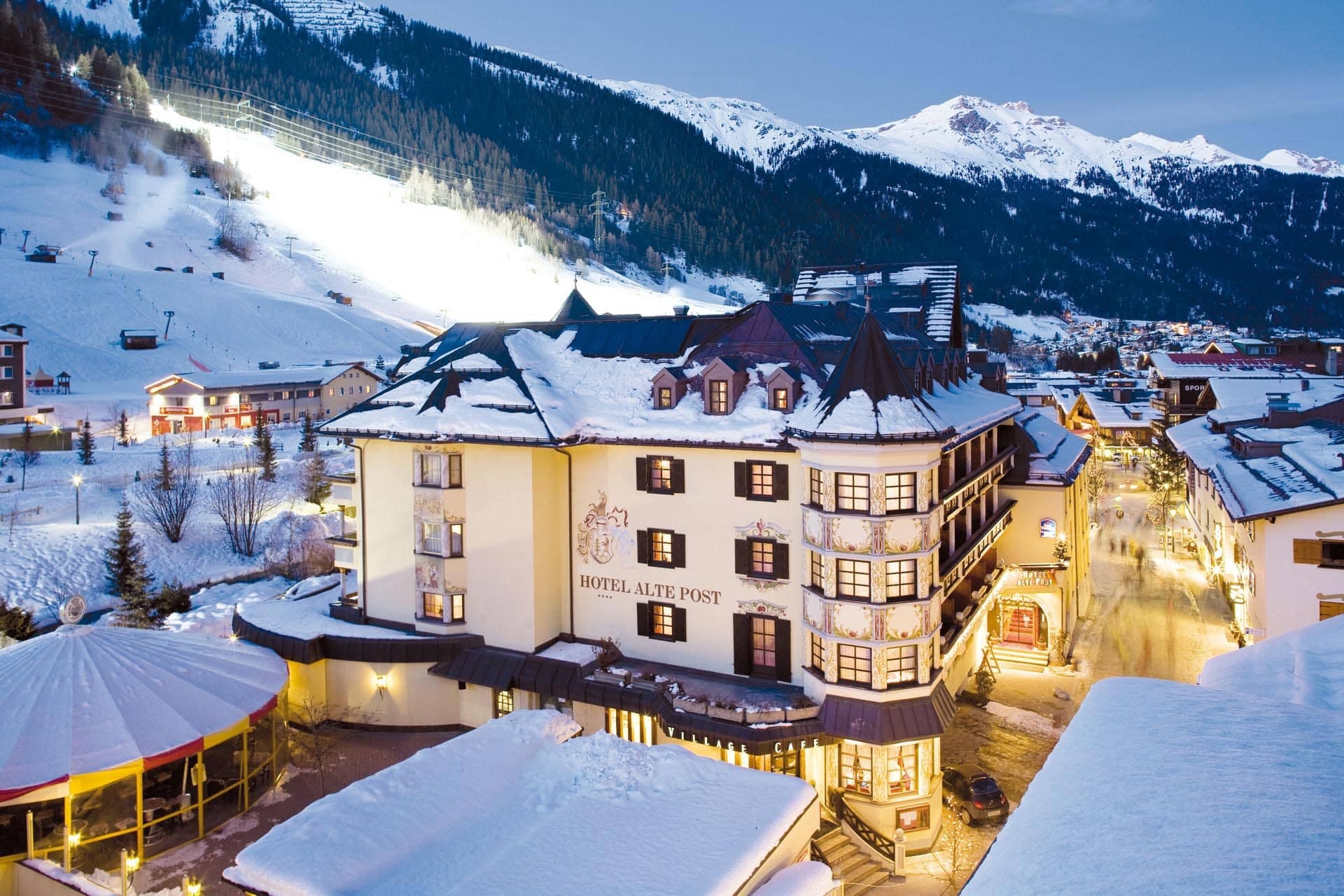 Hotel exterior in village center with nearby lighted ski slopes