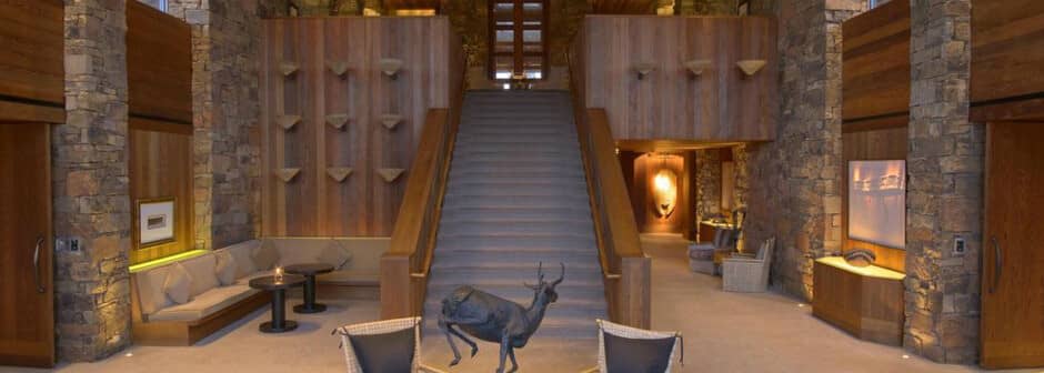 Grand entryway with stone pillars, wood paneling, and central staircase