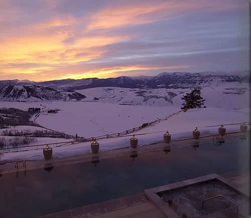 Infinity pool and inset hot tub with snow-covered mountain views