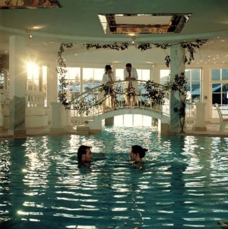 Indoor pool area with decorative bridge and skylight features