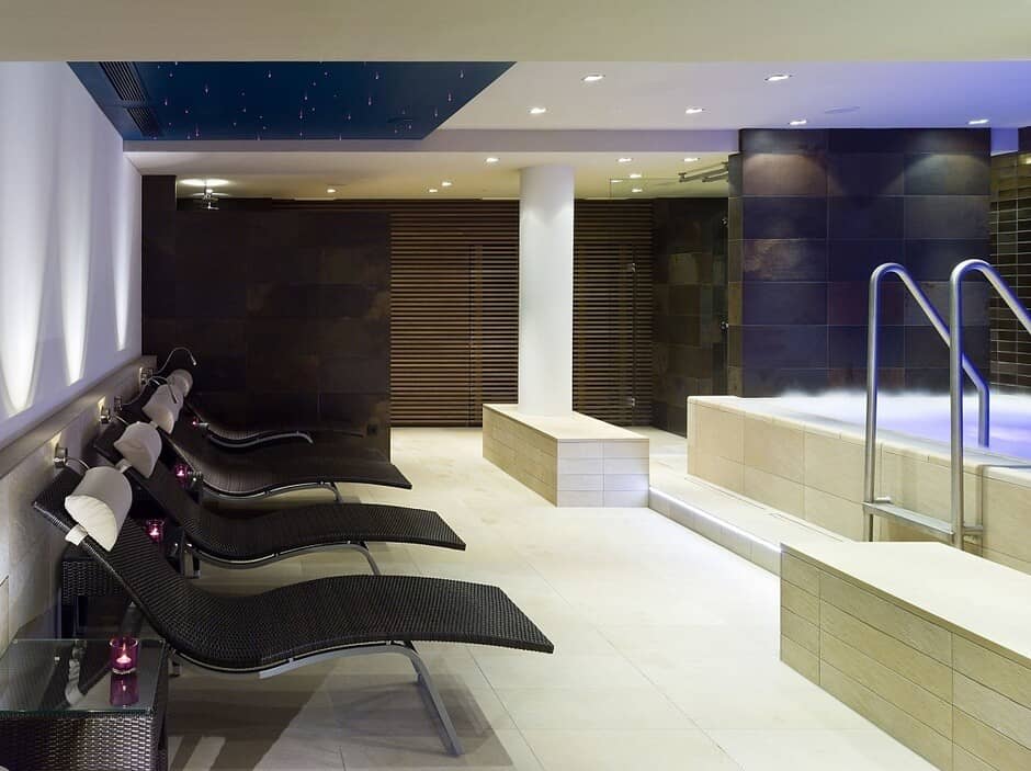 Indoor spa area with heated pool and four ergonomic lounge chairs