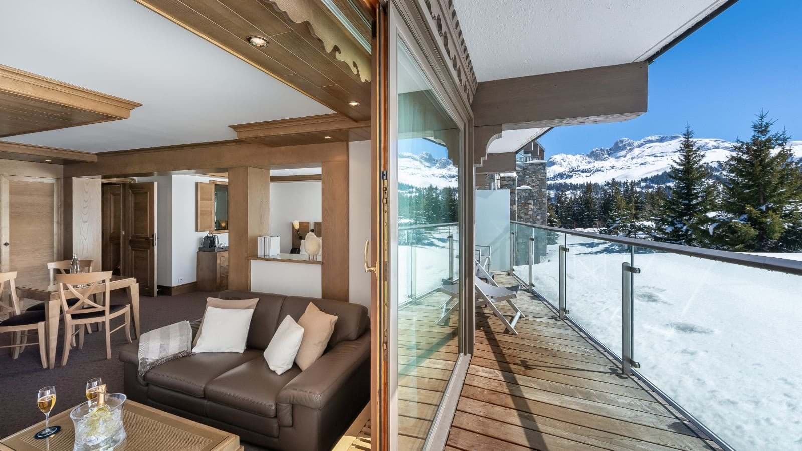 Living area with floor-to-ceiling glass doors and private mountain-view balcony