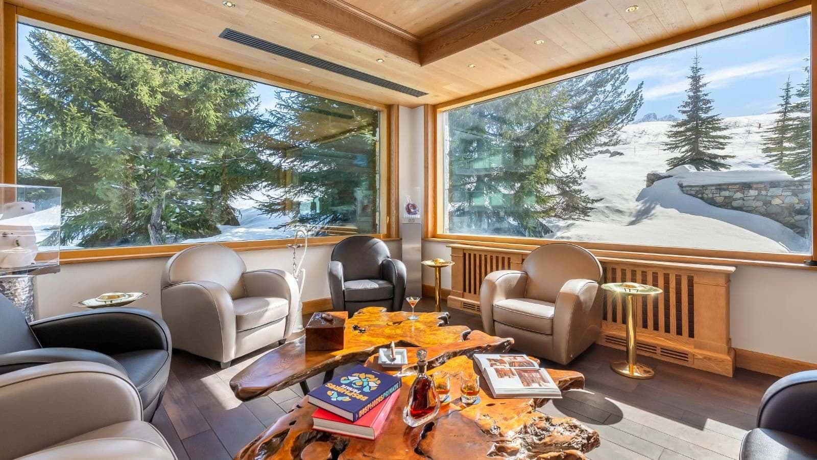Lounge area with leather armchairs and floor-to-ceiling snow views