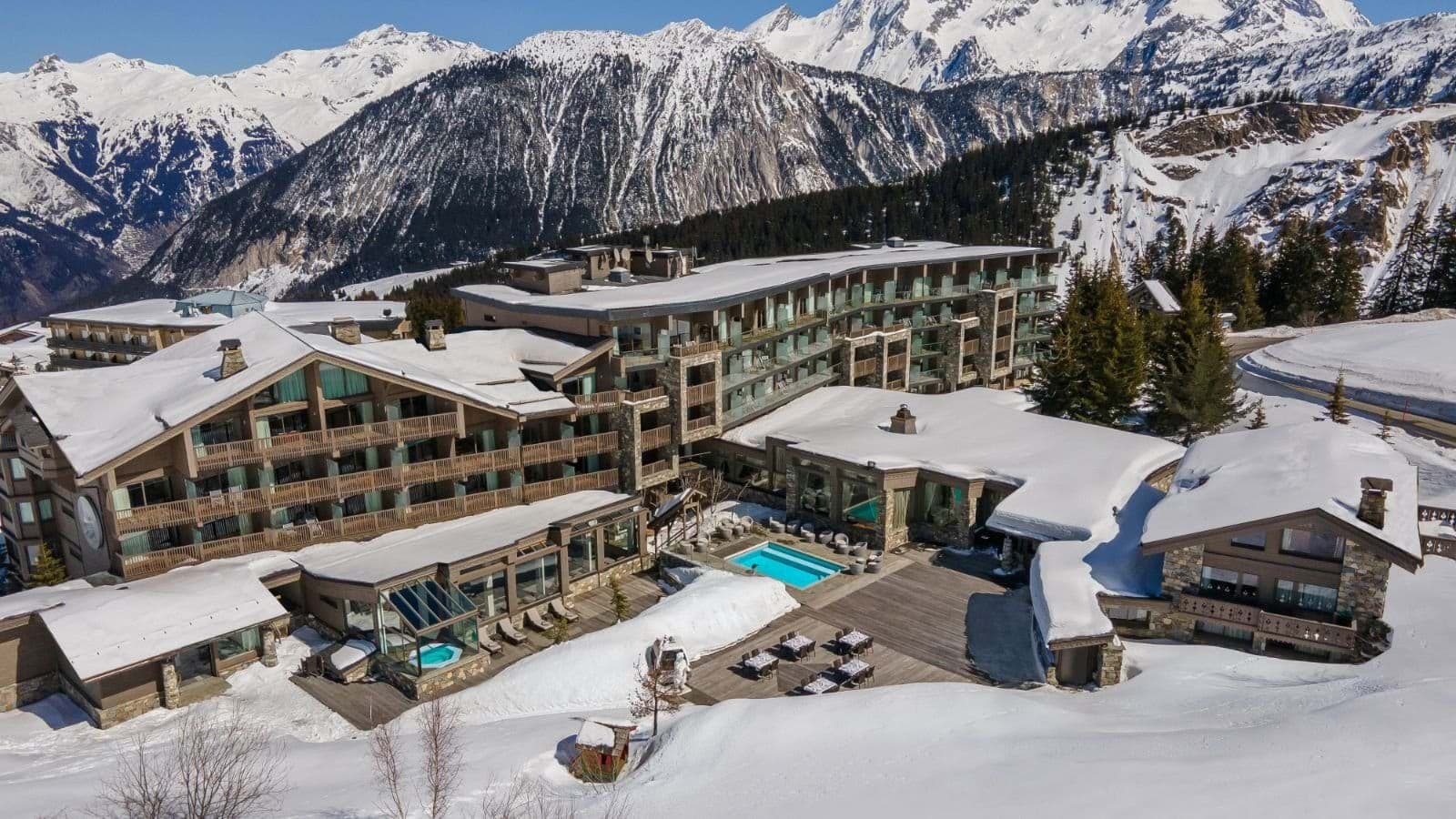 Ski-in/ski-out resort exterior with heated outdoor pool and mountain backdrop