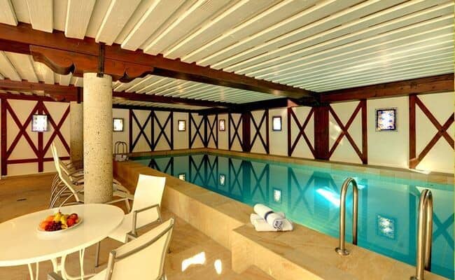 Indoor heated pool with poolside lounge seating and dining table