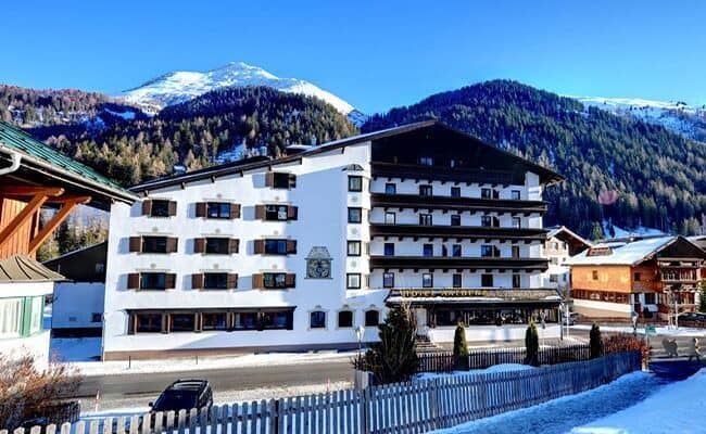 Hotel exterior with private balconies and snow-capped mountain backdrop
