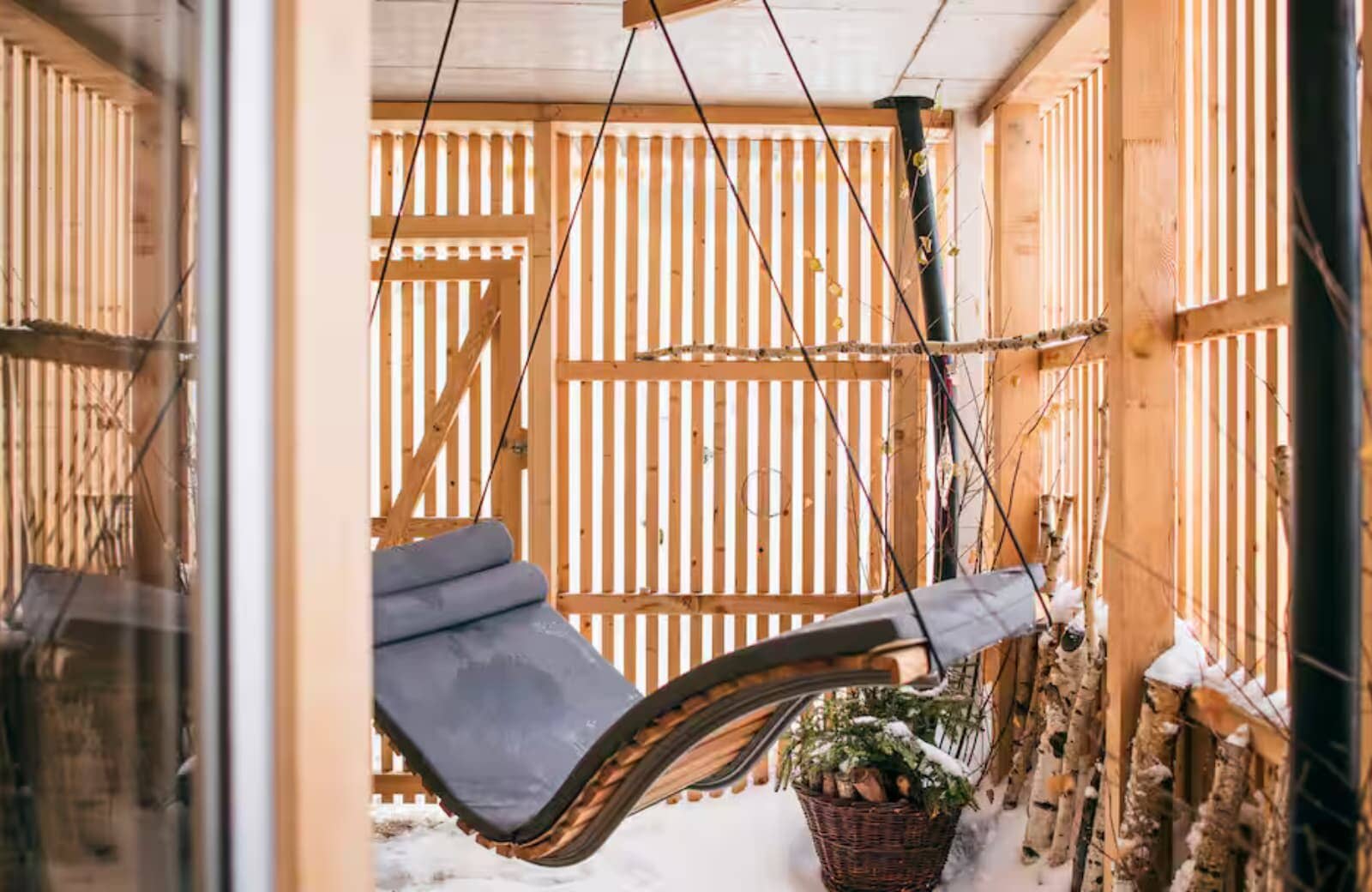 Covered porch with hanging daybed and slatted wood privacy walls