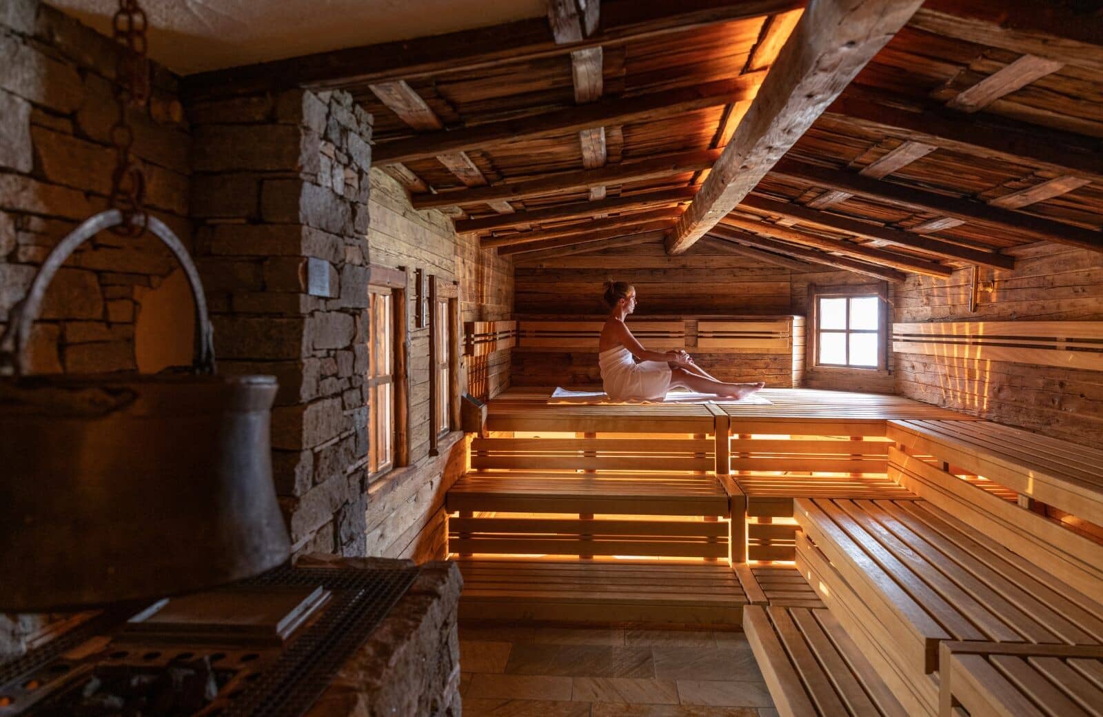 Wood-lined sauna with multi-level bench seating and stone heater