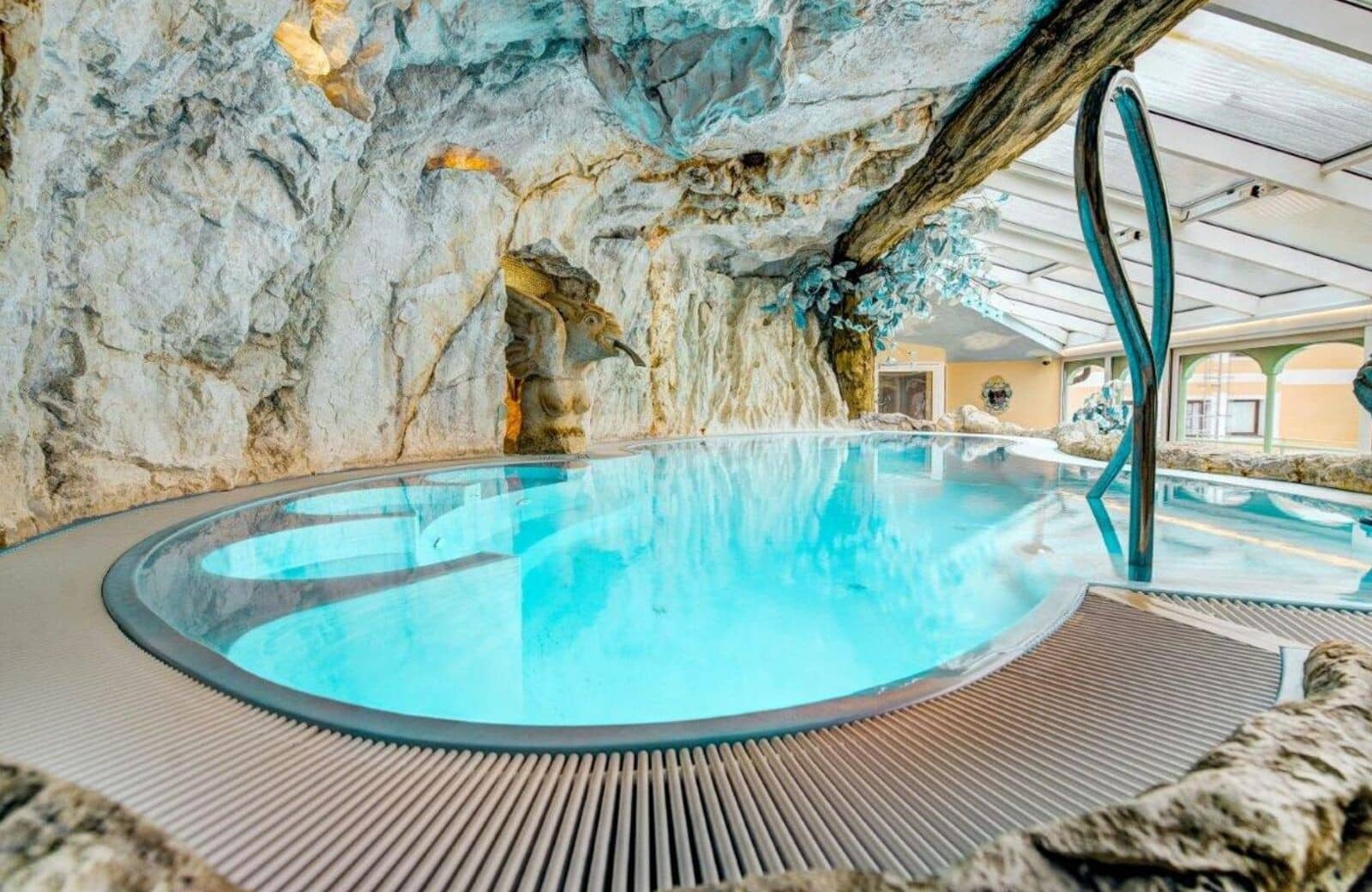 Indoor grotto pool with stone gargoyle fountain and glass ceiling