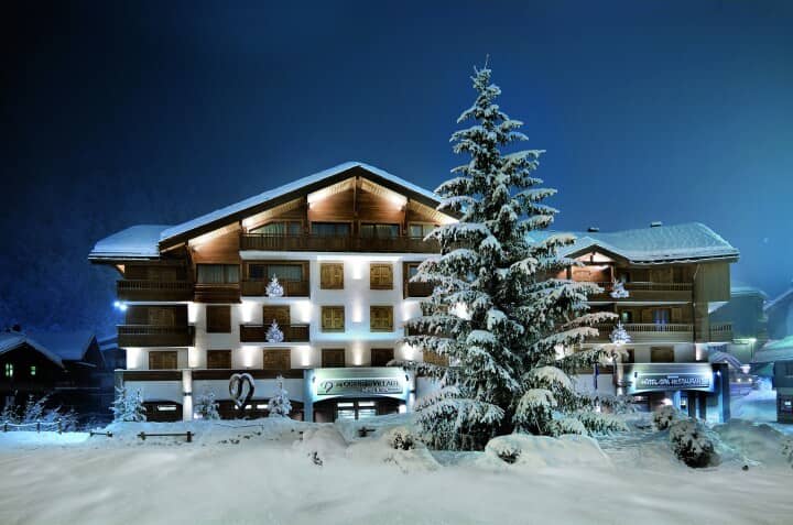 Chalet exterior at night with private balconies and snow-covered grounds