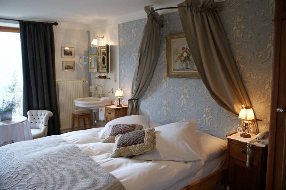 Guest bedroom featuring canopy bed and ensuite pedestal sink
