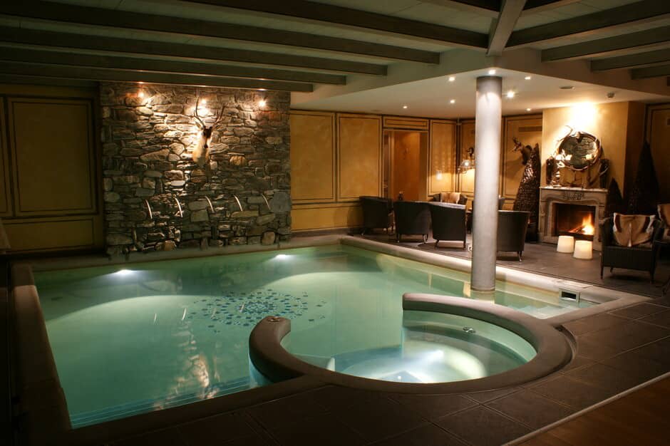 Indoor pool with integrated hot tub and fireplace lounge area