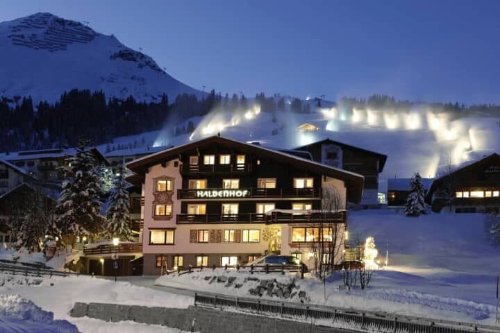 Chalet exterior at night with illuminated ski slopes in the background