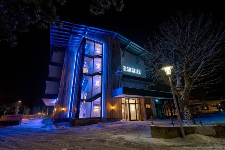 Building exterior at night with blue LED-lit staircase and wood siding