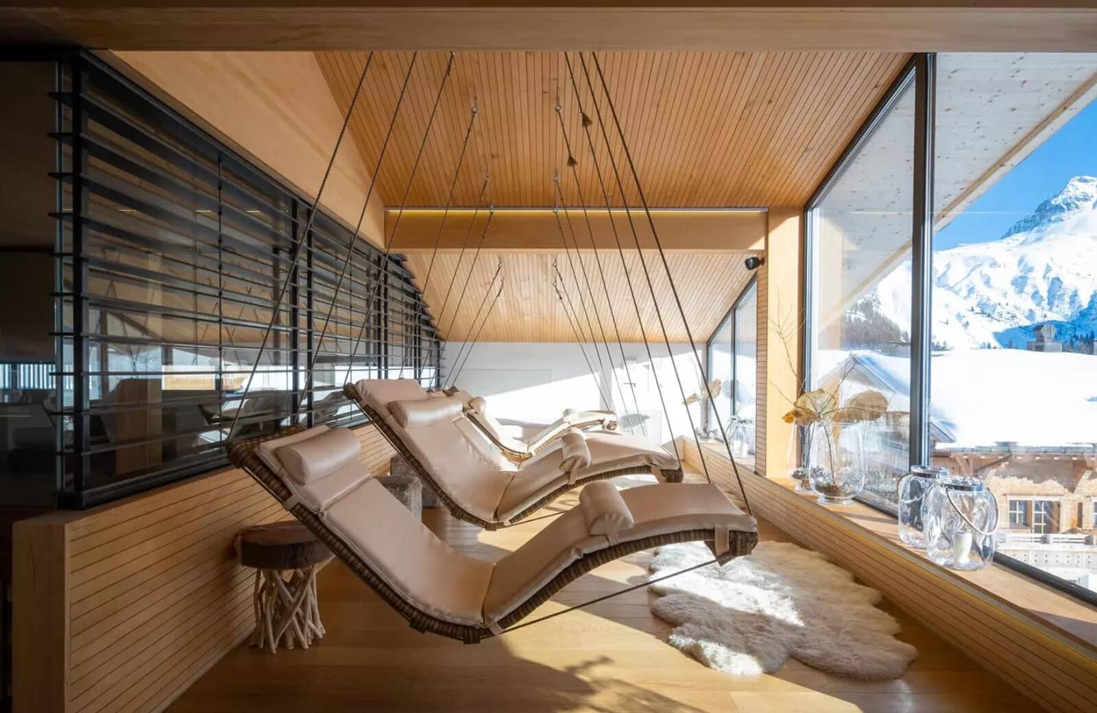 Sunroom with suspended loungers and floor-to-ceiling mountain views