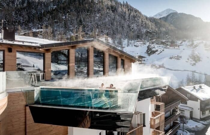 Cantilevered glass infinity pool with heated water and alpine valley views