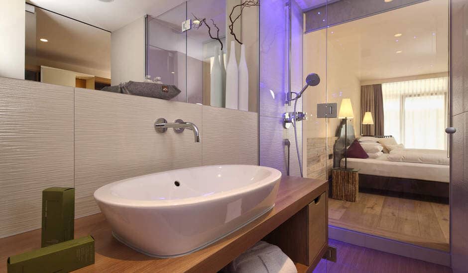 En suite bathroom with glass partition wall viewing the bedroom