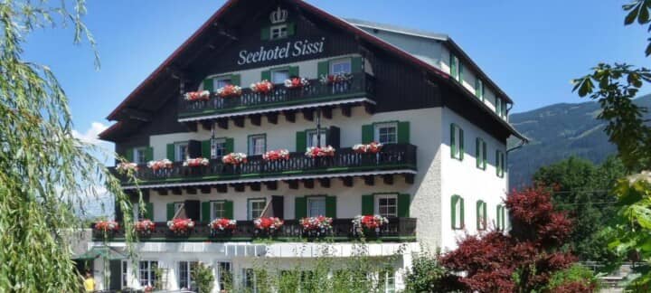Seehotel Sissi exterior featuring tiered flower-lined balconies and mountain backdrop