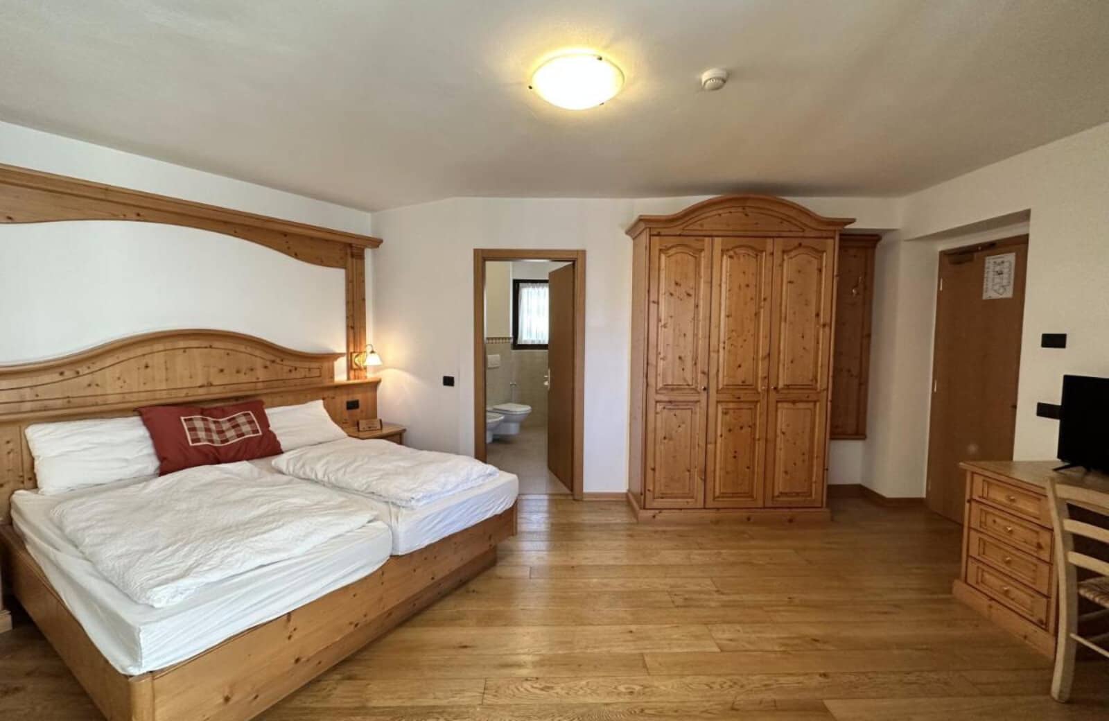 Bedroom with two twin mattresses, ensuite bathroom, and pine wardrobe