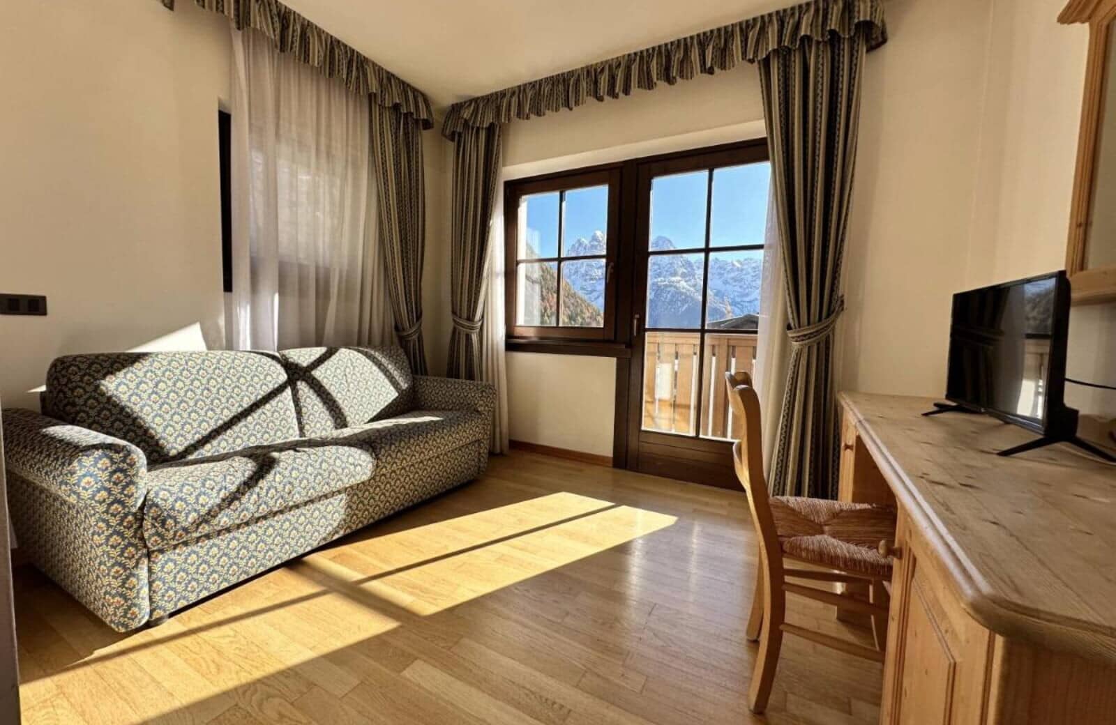 Living area with sofa bed, workspace, and mountain-view balcony