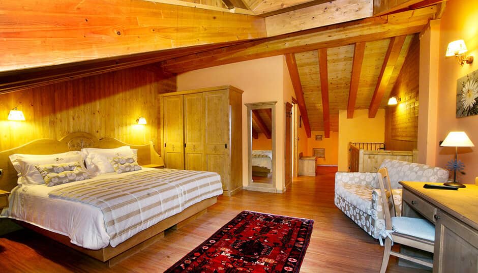 Loft bedroom with king bed, desk, and vaulted timber ceilings