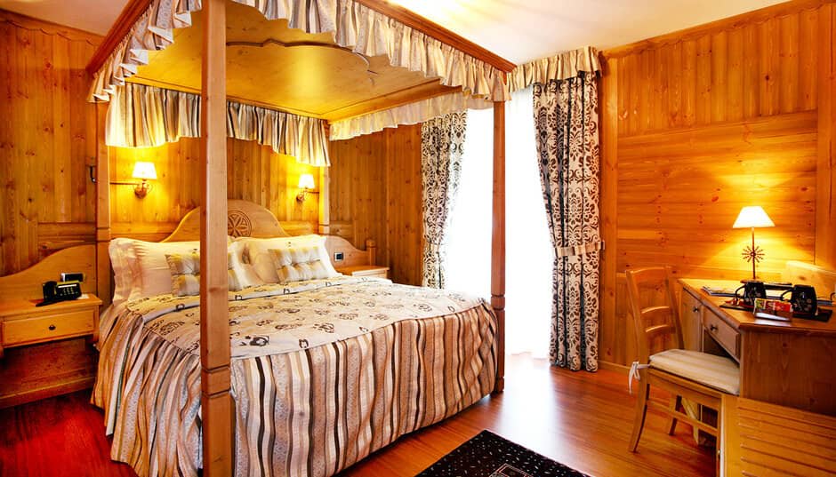 Wood-paneled bedroom with four-poster queen bed and dedicated work desk