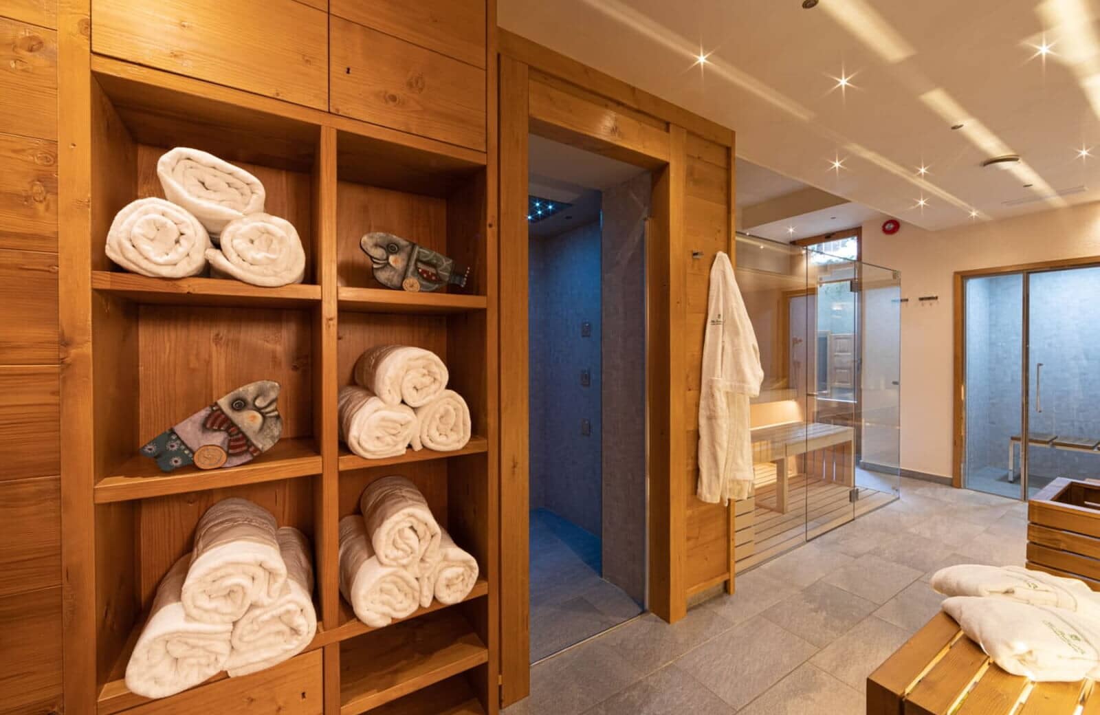Spa area with glass-enclosed sauna and walk-in shower with LED lighting