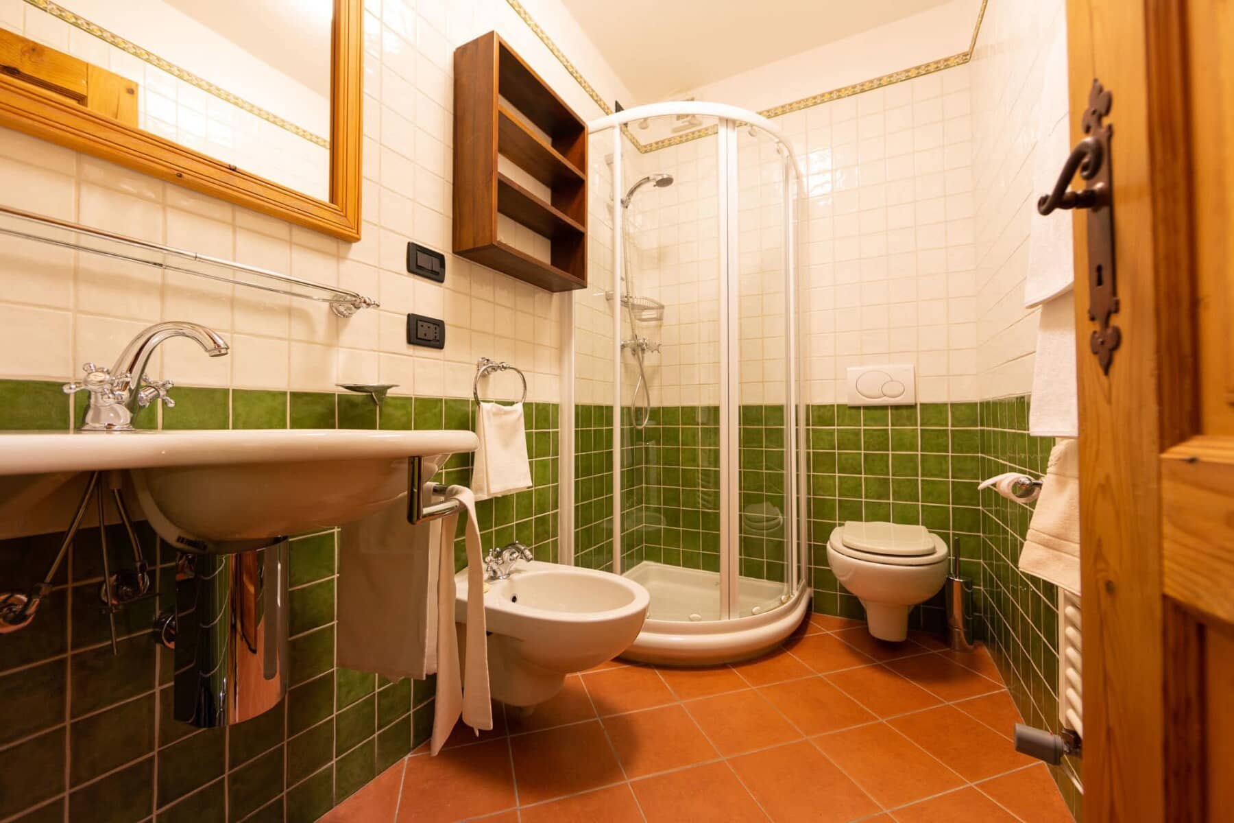 Bathroom with glass corner shower, bidet, and green tile accents