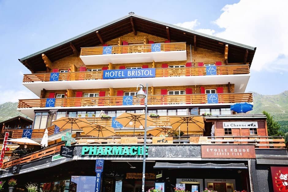 Hotel exterior with private balconies and ground-floor pharmacy and shops