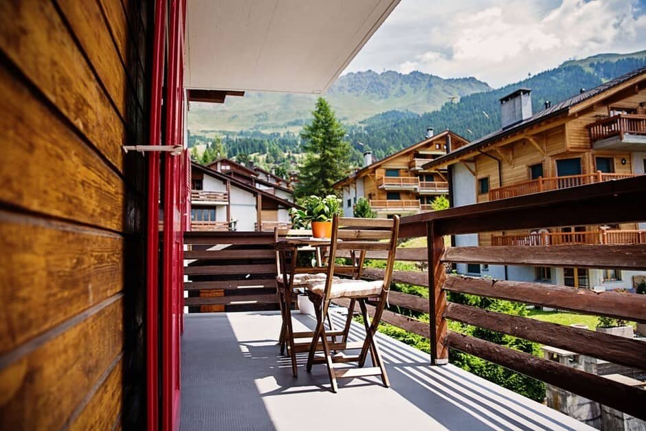 Covered balcony with seating for two and mountain village views