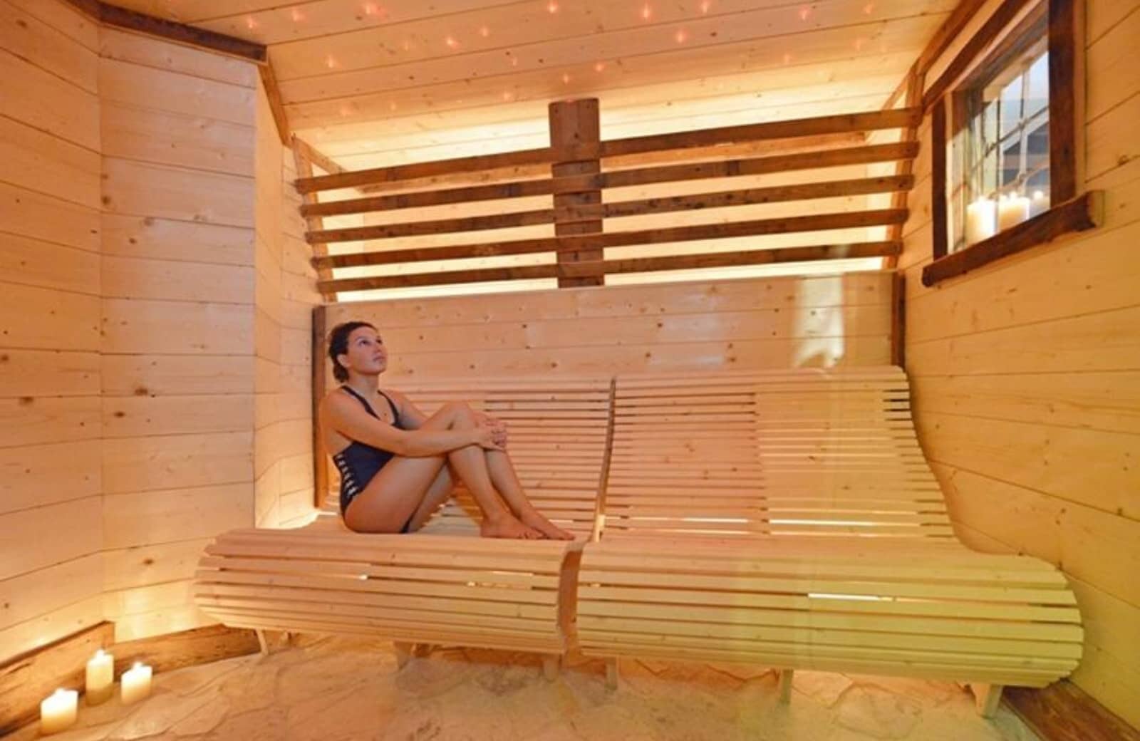 Private sauna featuring contoured wooden loungers and recessed ceiling lights
