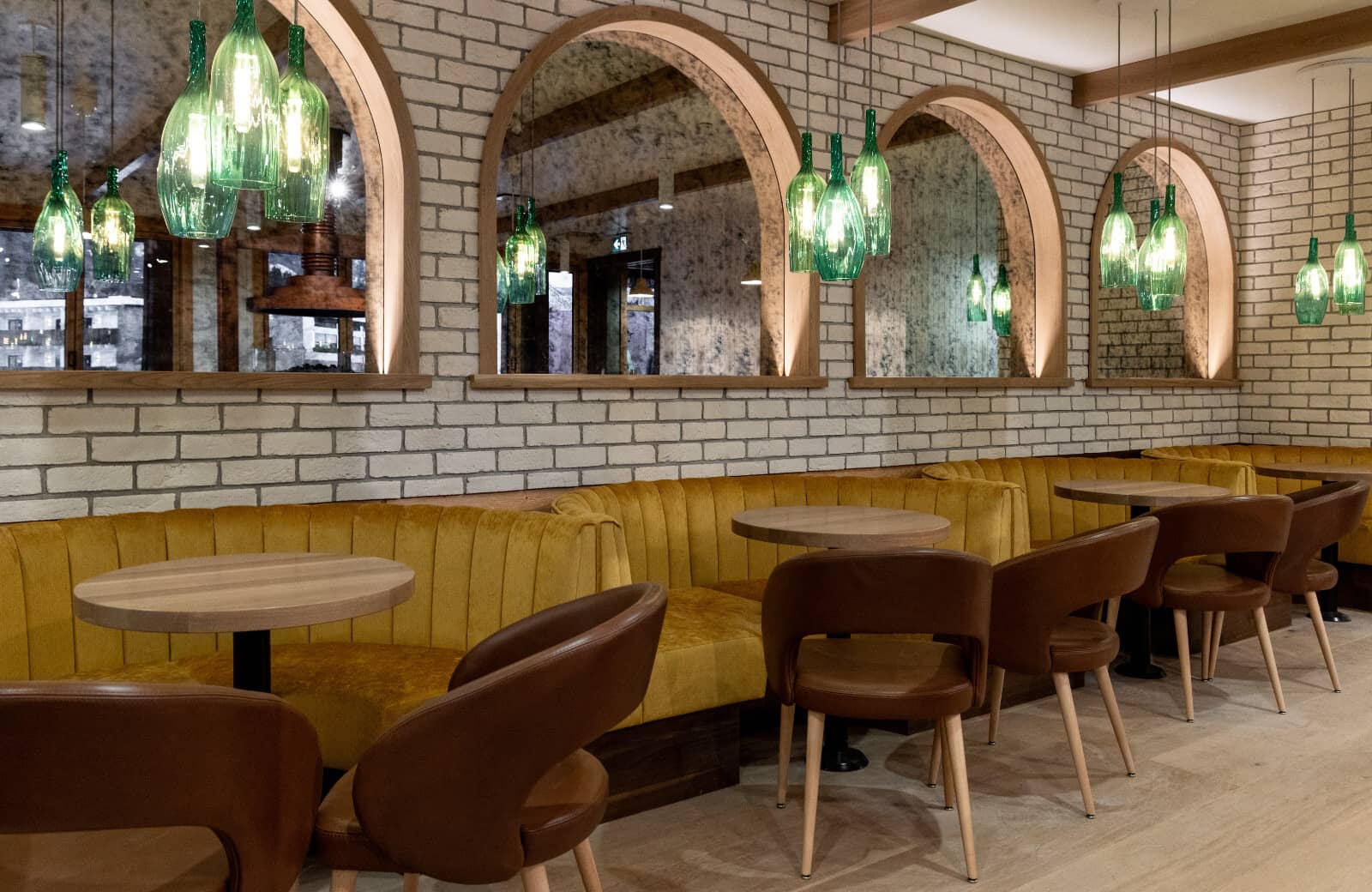 Dining area with velvet banquette seating and arched mirrors