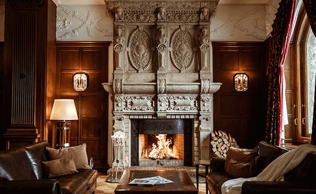 Wood-paneled living area with ornate stone fireplace and leather seating