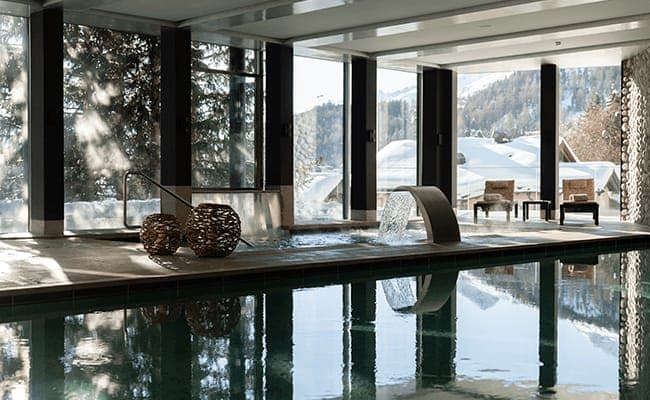 Indoor pool and hot tub with waterfall features and mountain views