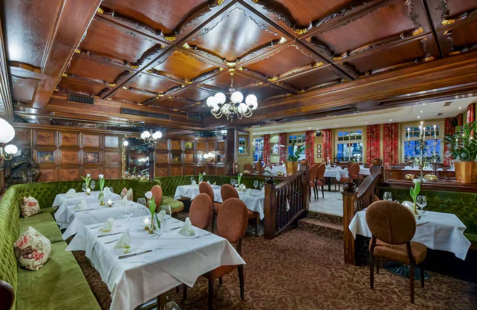 Dining area with ornate coffered wood ceiling and velvet banquette seating