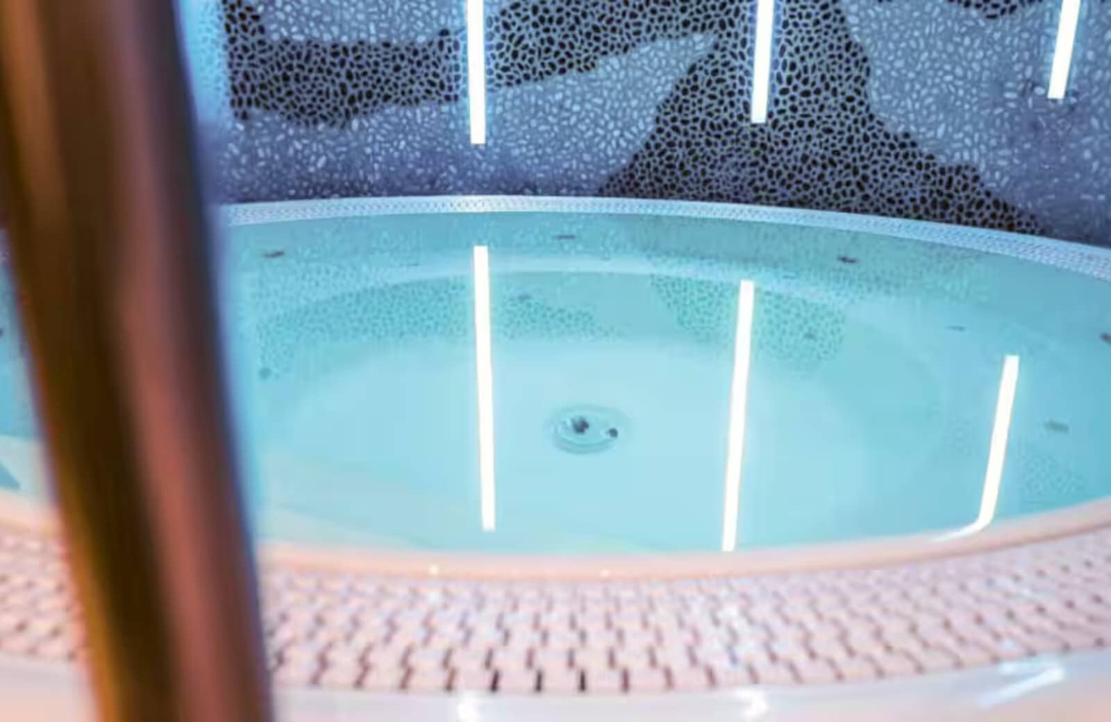 Indoor hot tub with pebble feature wall and accent lighting