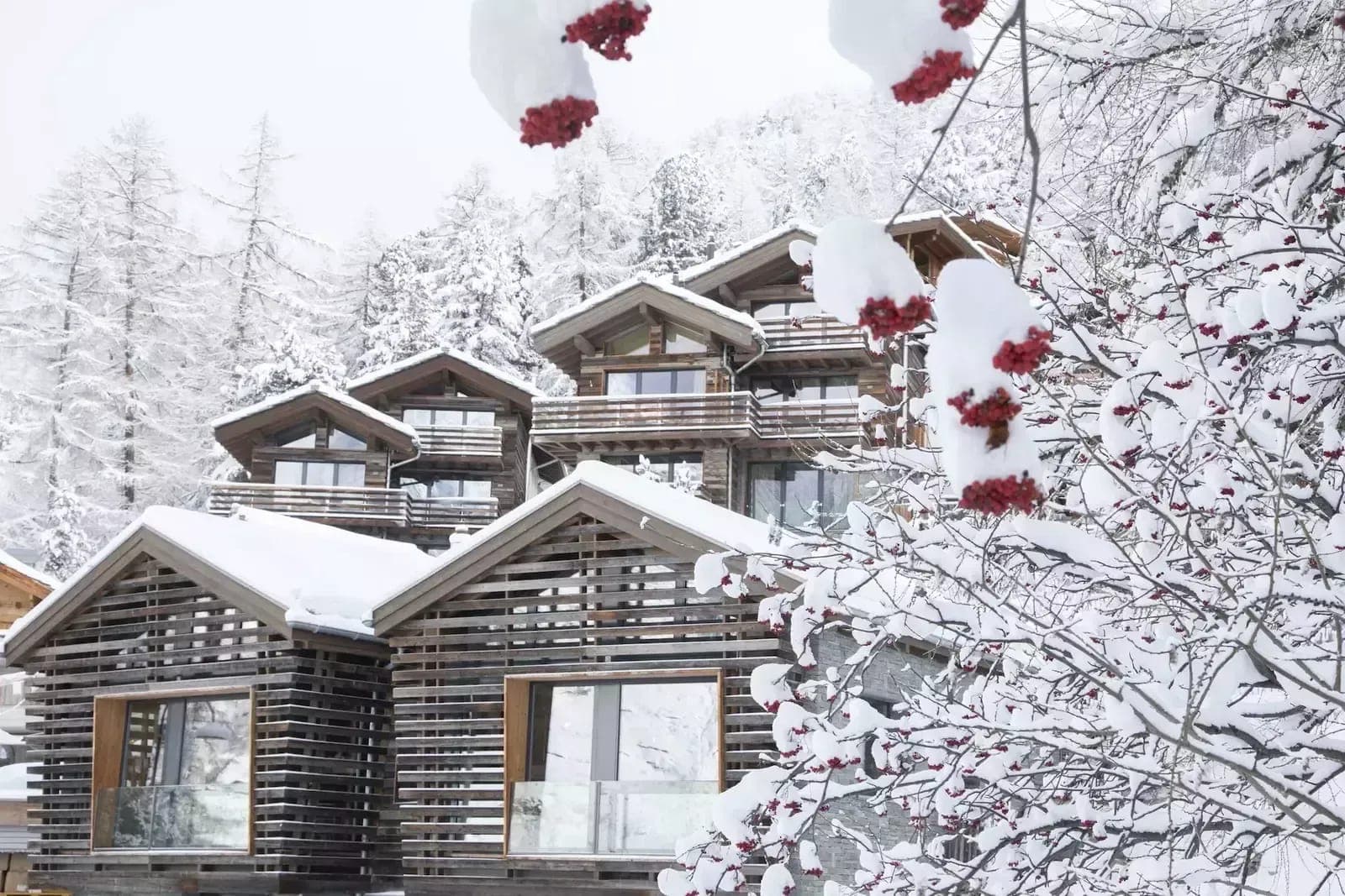 Alpine chalet with tiered balconies and snow-covered mountain backdrop