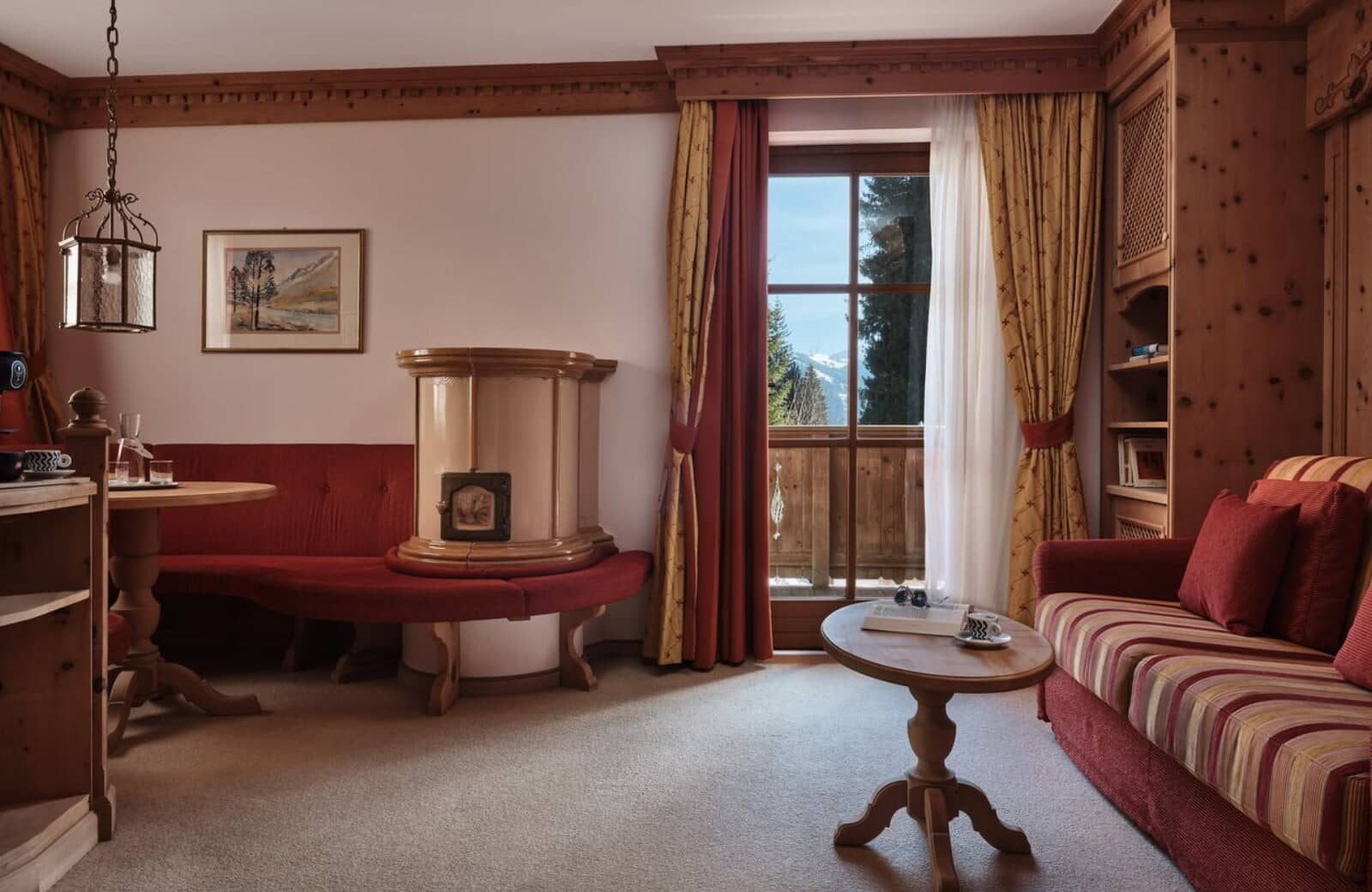 Living area with traditional Kachelofen stove and balcony mountain views