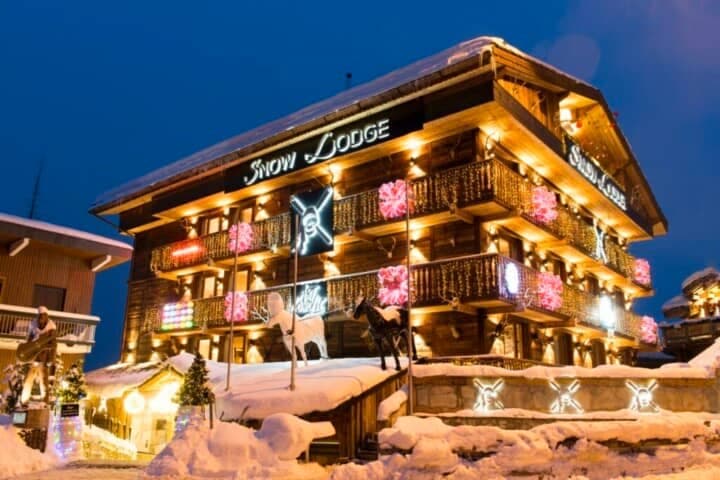 Chalet exterior with multiple wrap-around balconies and festive night lighting