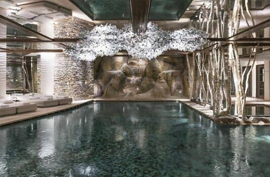 Indoor pool with grotto waterfall and poolside lounge seating