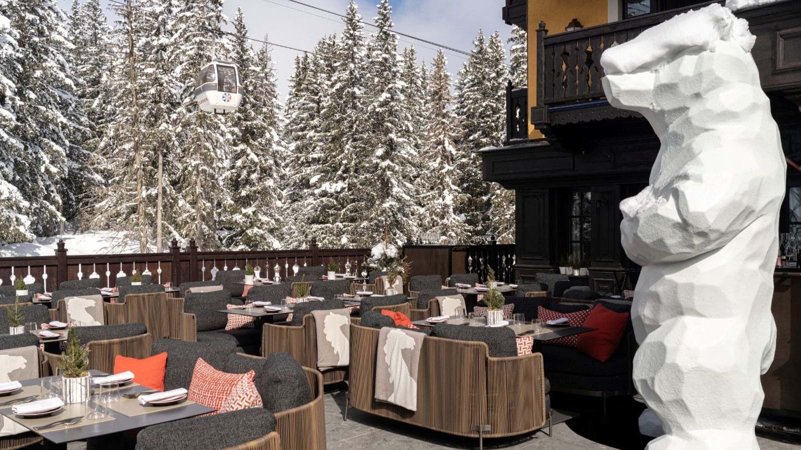 Outdoor terrace with dining tables and direct view of ski gondola