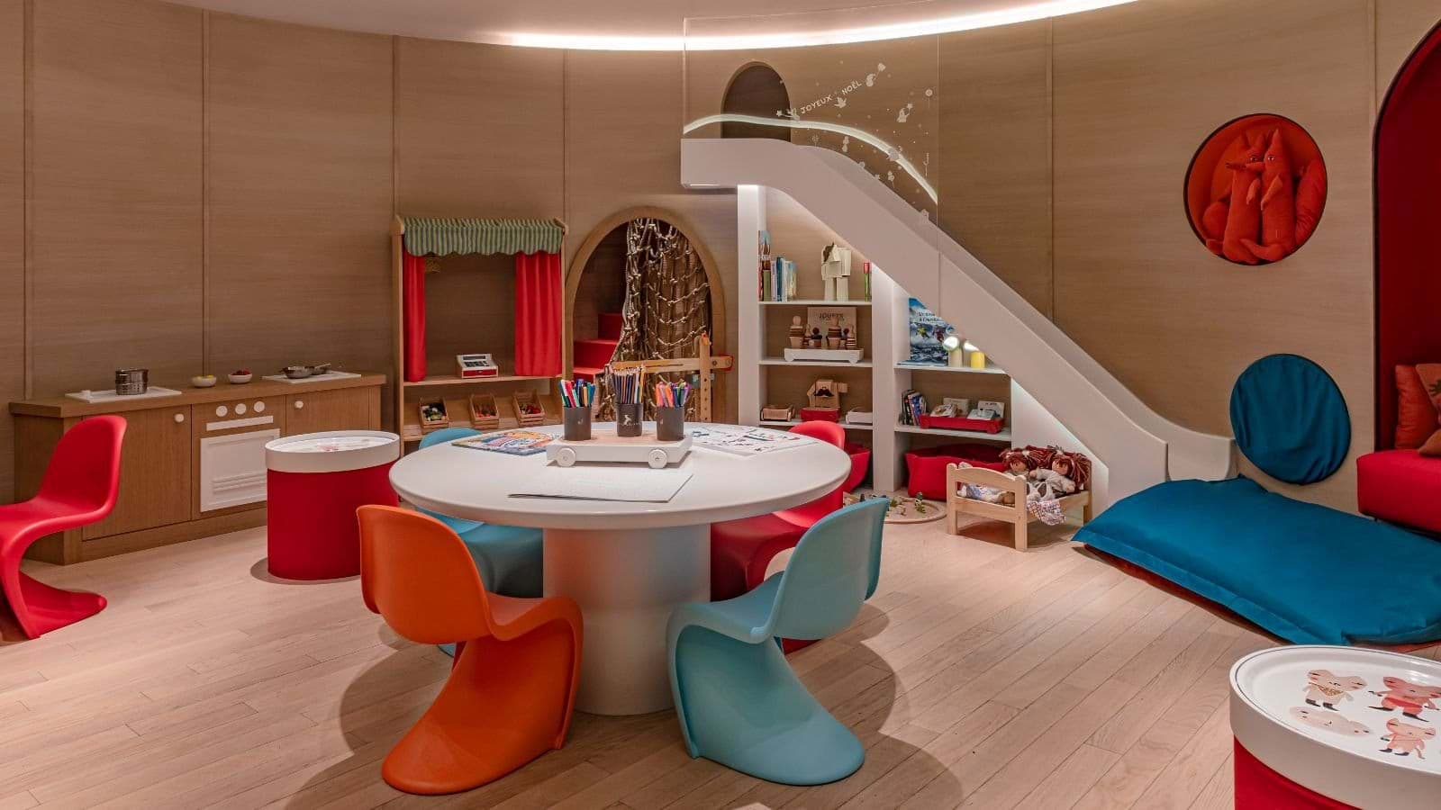 Kids' playroom with indoor slide and craft table seating six