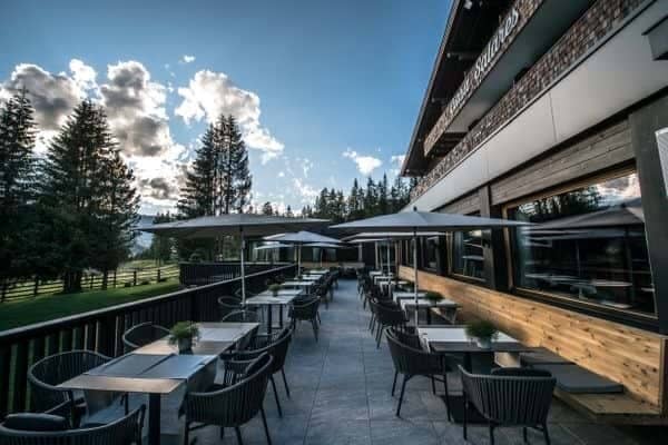 Outdoor terrace seating with forest views and umbrella-shaded dining tables