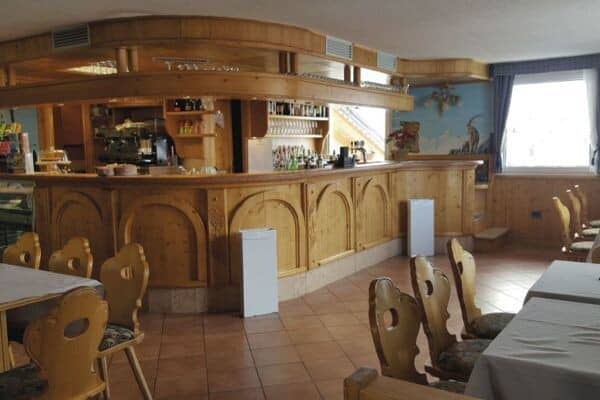 Pine-paneled bar area with espresso machine and traditional carved chairs