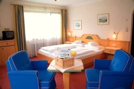 Guest bedroom with king bed and armchairs; built-in wood headboard