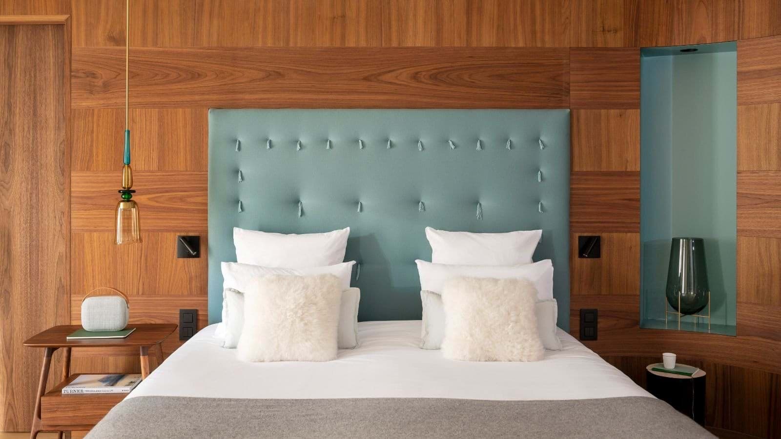 Bedroom with wood-paneled walls, integrated reading lights, and bedside power outlets