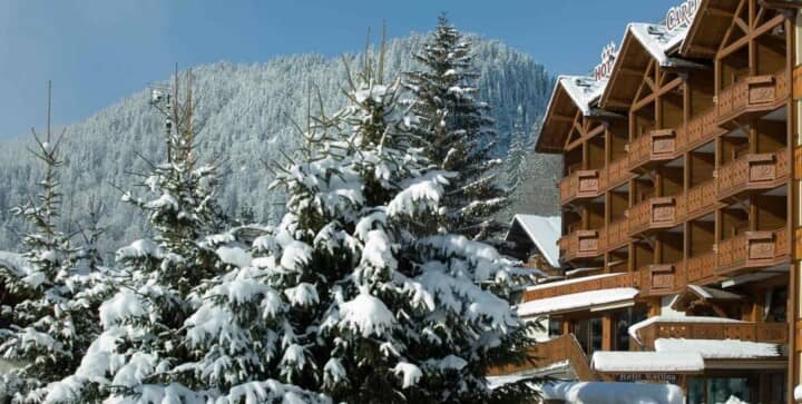 Timber chalet exterior featuring private balconies and immediate access to snowy pine forest
