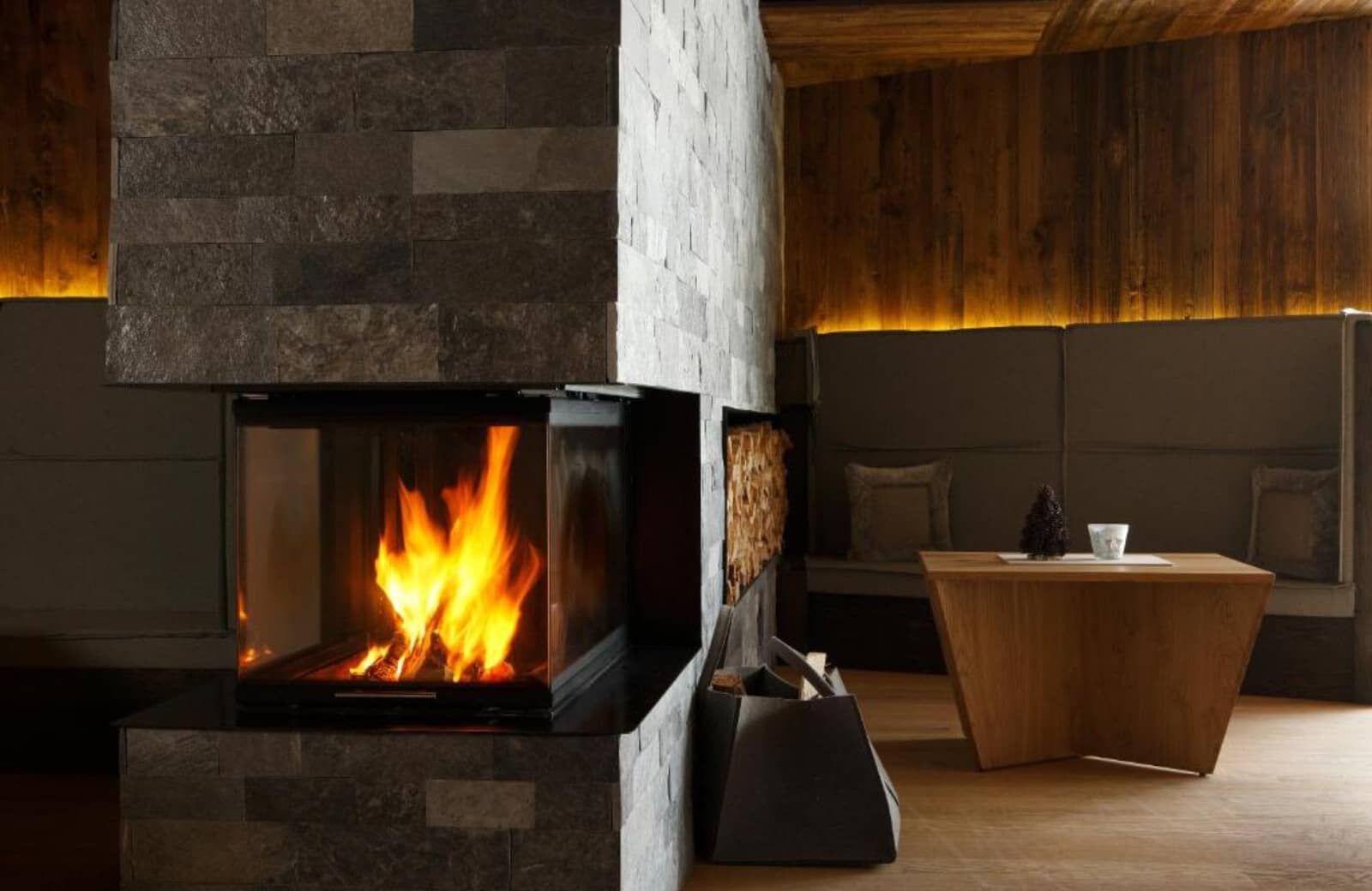 Stone fireplace with three-sided glass and built-in wood storage